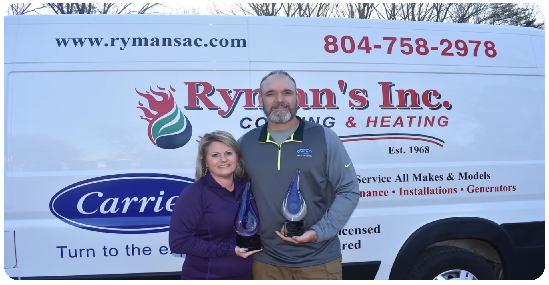 A man and woman holding up awards in front of a rymans logo.