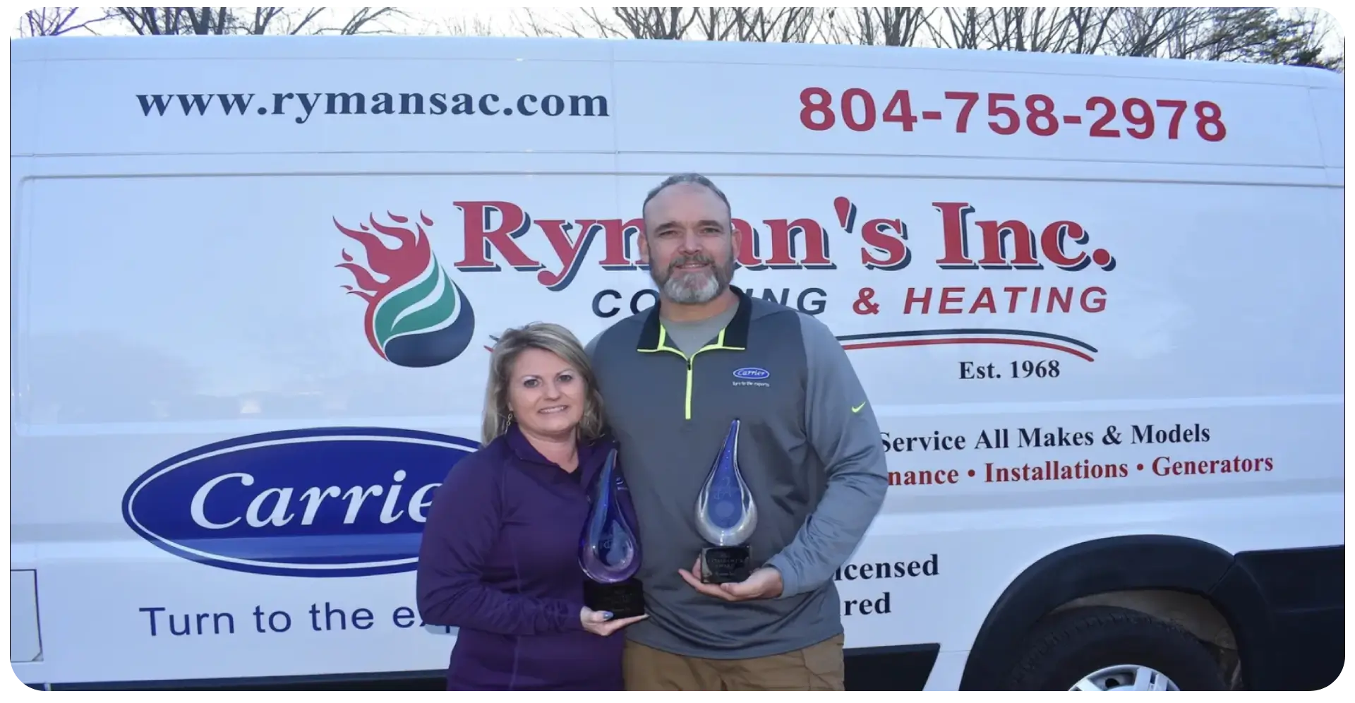 A man and woman holding up awards in front of a rymans logo.